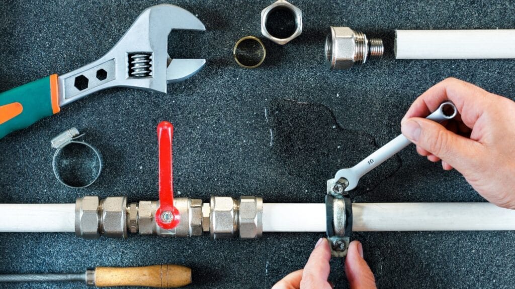 Plumber repairing a pipe valve with an adjustable wrench in Longmont