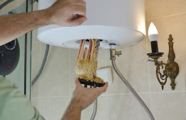 Technician removing mineral buildup from a water heater in Longmont