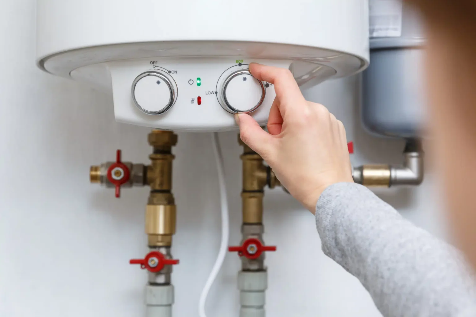 Homeowner adjusting the temperature controls on a water heater in Longmont